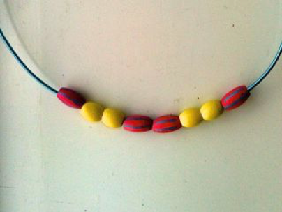 Foto av et smykke med røde og gule perler 
