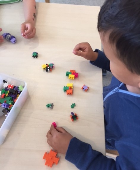 Et barn i ferd med å bygge lego-snurrebass