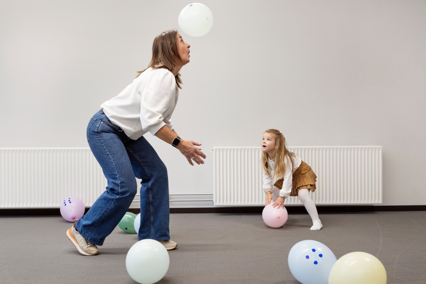 en voksen gjør talltriks med ballong, med et entusiastisk barn som ser på.