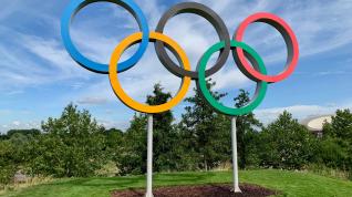 Olympiske ringer plassert i luften over en gressbakke