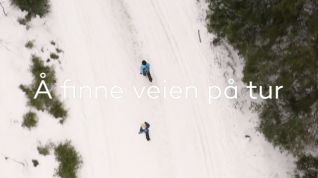 Dronefoto av to barn som løpet i skiløype