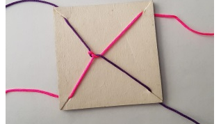 Pappkort med to tråder som er knytt sammen. Trådene er festet i fire hjører på kortet.