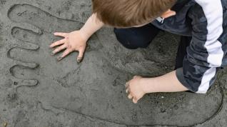 Et Kjempestor i sanden, en gutt leggen hånden sin i sporet