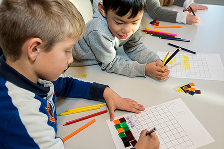 Elever på barnetrinn som løser matematiske oppgaver med fargeblyanter og brikker.Foto